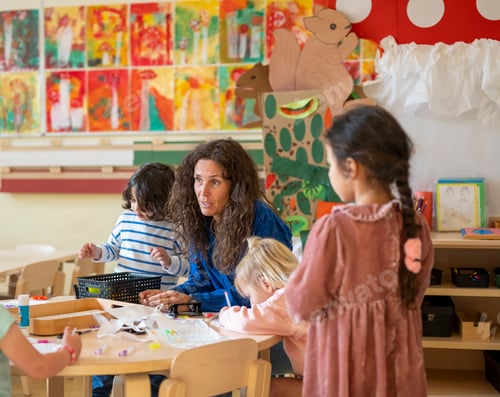 Preview: Happy encouraging teacher speaking to her class, young group of children listening to their lesson