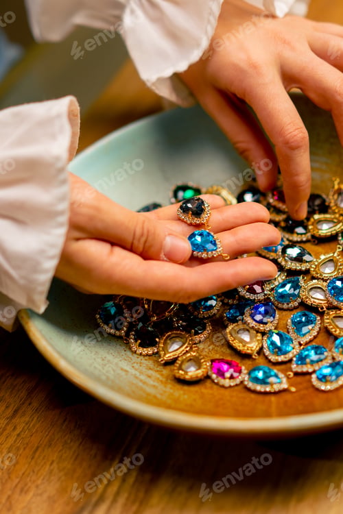 Preview: female hands holding multi-colored stones and pendants for necklace craft jewelry making home