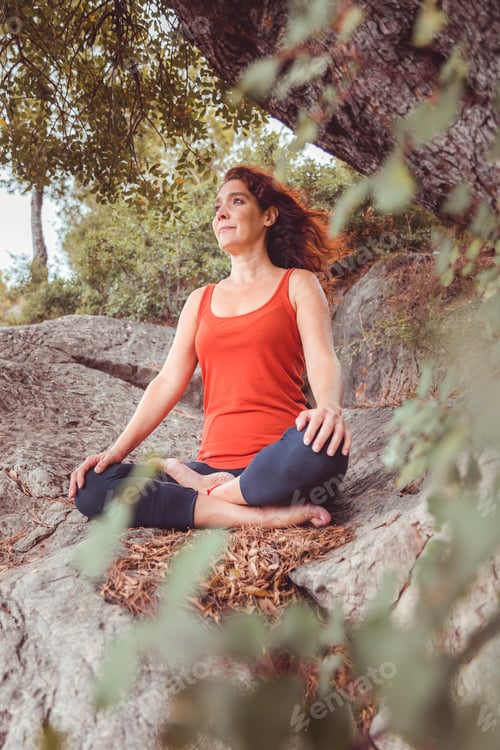 Preview: Woman seated in lotus position on rock.