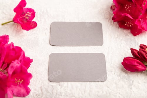 Preview: Gray business card with purple azalea flowers on gray concrete background. side view, copy space.
