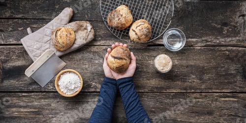 Preview: Top view of male hands holding fresh home made bread bun