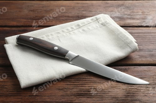 Preview: One sharp knife and napkin on wooden table, closeup