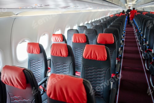 Preview: Empty interior of cabin of airplane with rows of black and red seats in daytime before the flight