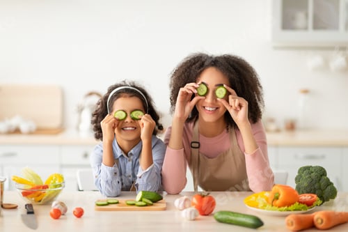 Vista previa: Black mom and daughter playing with food in the kitchen