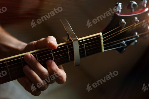 Preview: A man's hand on the fretboard of a guitar runs his fingers through the strings and clamps