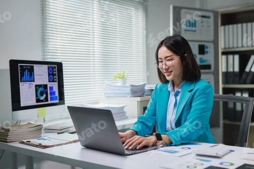 Preview: Young businesswoman analyzing data on laptop in office