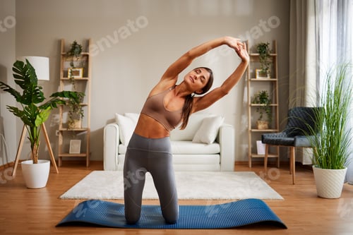 Preview: Young woman working out at home and doing stretching
