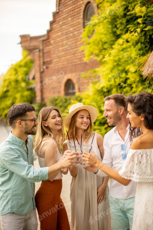 Preview: Group of happy young people cheering with fresh lemonade in the garden