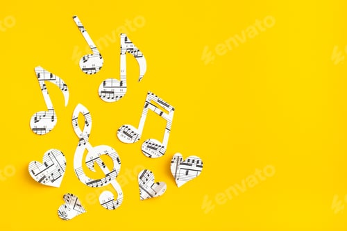 Preview: Musical notes, clef and hearts cut from paper with musical text on yellow background. Copy space