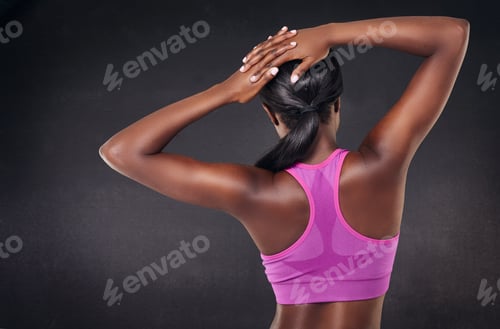 Preview: Rearview studio shot of a fit woman stretching against a black background