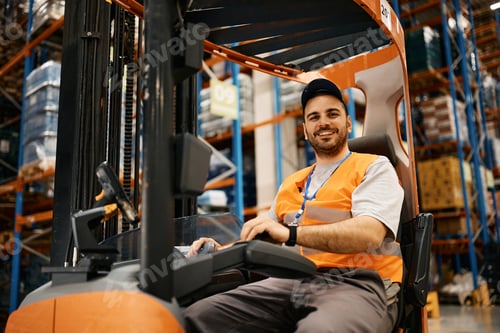 Preview: Happy forklift operator working at distribution warehouse and looking at camera.