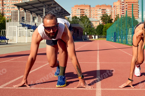 Preview: Young sporty woman and man are ready to run on racetrack. Fit well formed people are at large nice