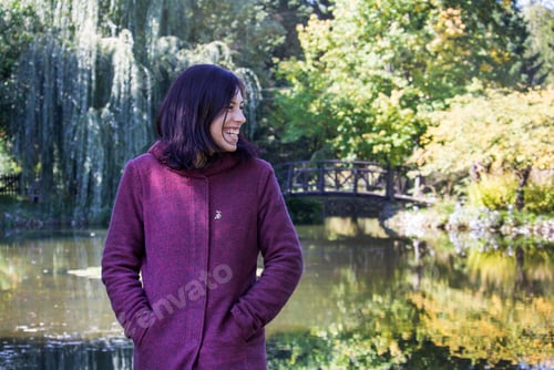 Preview: Portrait of smiling young woman against a trees and water