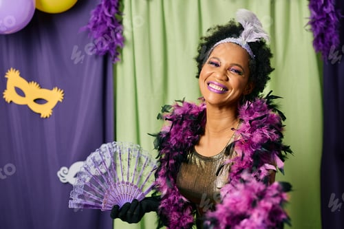 Preview: Happy African American woman in carnival costume during Mardi Gras party looking at camera.