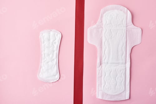 Preview: Two sanitary pads and red ribbon on a pink background