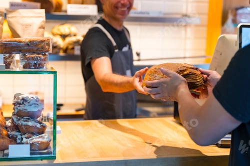 Preview: Customer in the bakery shop buying a loaf from the baker in the workshop