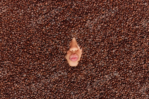 Preview: Creative shot of womans face covered with fragrant coffee beans keeps lips folded prepares aromatic