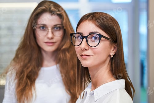 Preview: Charming young women in glasses standing in optical shop