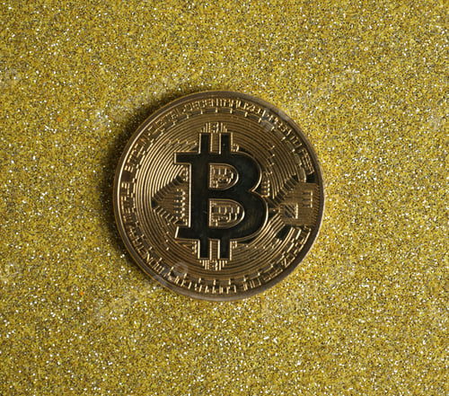 Preview: Bitcoin on golden glittery surface, top view