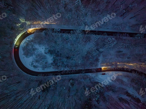 Preview: Headlights of car illuminating winding road after dark in winter.