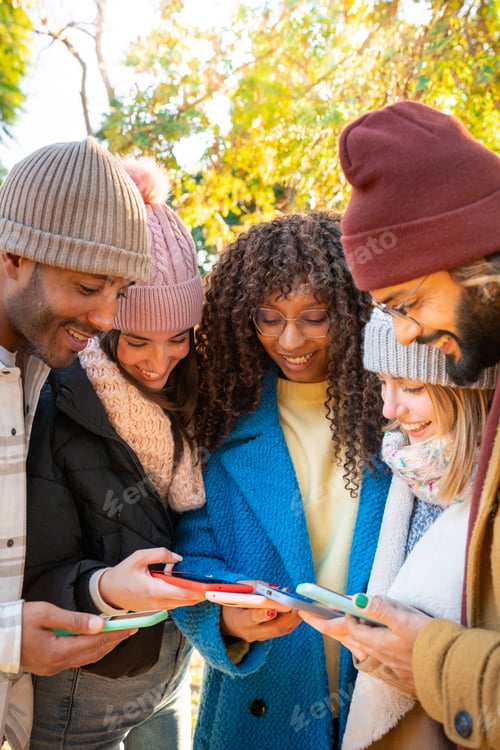 Preview: Group of young multi-ethnic friends using cell phones outdoors. People addicted to technology.