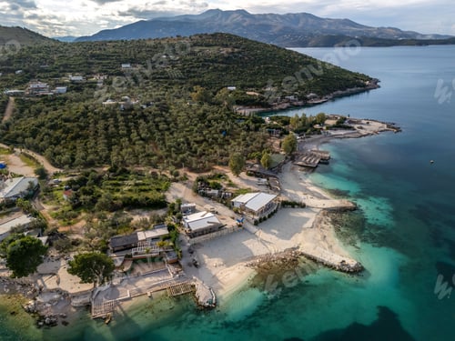 Preview: Aerial view of Ksamil resort village surrounded by teal waters and majestic mountains. Albania