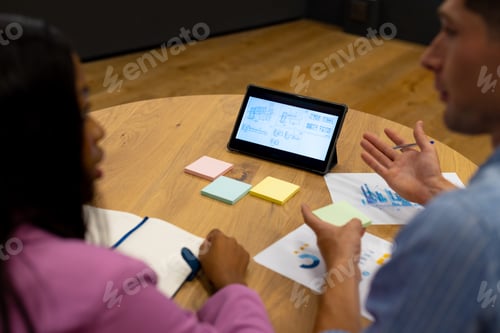 Preview: Diverse male and female colleagues in discussion using tablet in casual office meeting