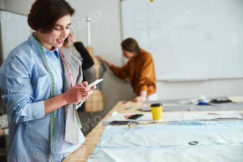Preview: Woman couturiere clicking on her mobile phone