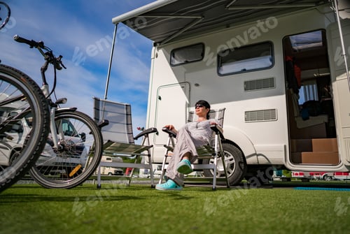 Preview: Woman resting near motorhomes in nature. Family vacation travel,