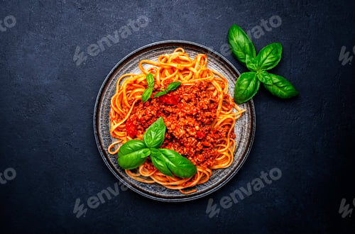 Preview: Spaghetti pasta with minced veal meat in tomato marinara sauce with basil, black background