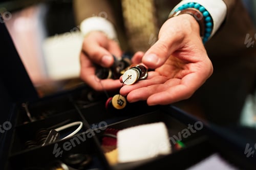 Preview: Close-up of fashion designer choosing buttons in drawer