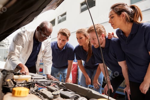 Preview: Mechanic instructing trainees around a car engine, low angle