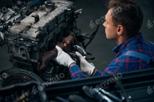 Preview: Male installing exhaust manifold on machine engine