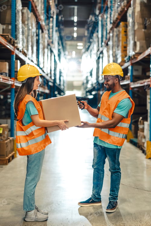 Preview: Multiracial warehouse workers handling a box in aisle with safety gear on.