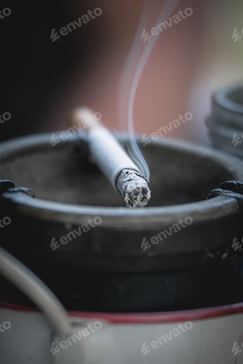 Preview: Vertical shot of a burning cigarette on an ashtray