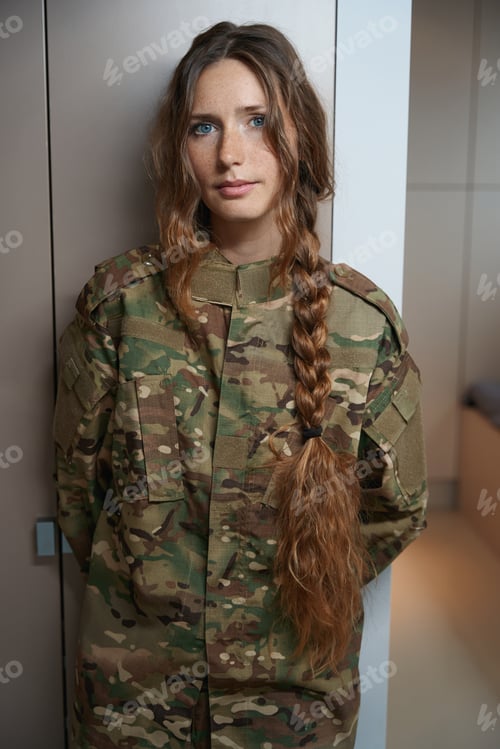 Preview: Woman in a camouflage uniform stands by closet in room