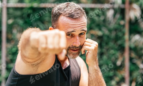 Preview: Live strong. Muscular man in black sportswear training outdoors. Copy space on the right side.