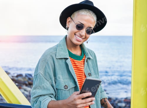 Preview: Happy hipster woman with smartphone on the beach