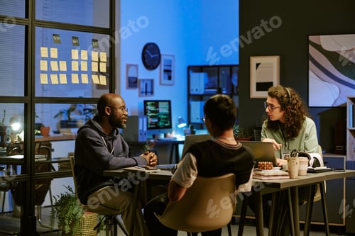 Preview: Multiethnic Young Adults Collaborating during Evening Office Meeting