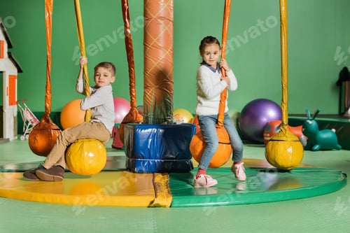 Preview: cute happy little kids looking at camera while swinging in entertainment center