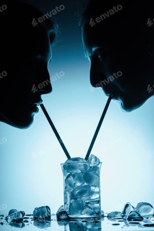 Preview: silhouettes of girls drinking cold water with ice cubes from one glass with straws