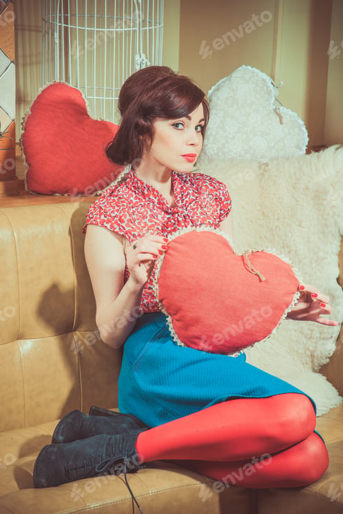 Preview: Young Girl In Red Stockings Sits On A Couch And Holding A Big Red Heart