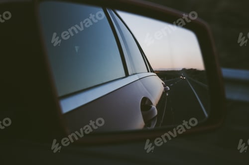Preview: Focus on foreground of a rear mirror. Driving. Road trip. Vanishing point.