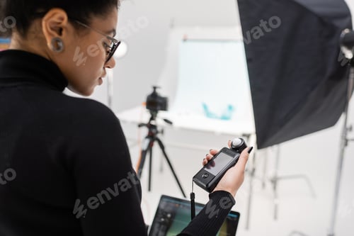 Vista previa: productor de contenido afroamericano en cuello alto negro mirando el medidor de exposición en una foto borrosa