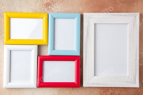 Preview: Close up view of small and big colorful photo frames hanging on nude color wall with free space