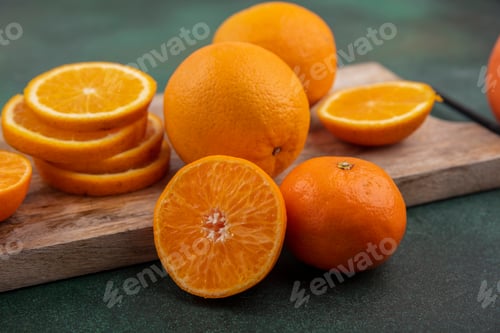 Preview: side view orange slices on a cutting board on a green background