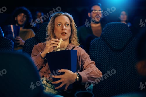 Preview: Young woman watching a tense movie at cinema.