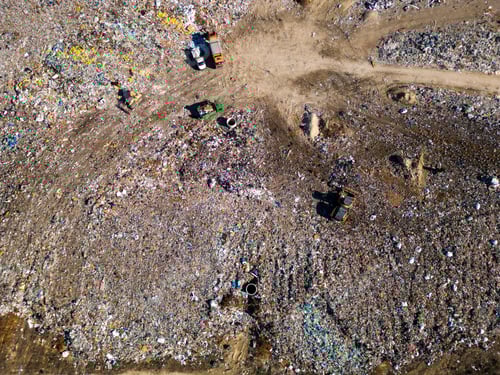 Preview: Aerial view of a vast landfill, where bulldozers are working and trucks are bringing new waste, huge