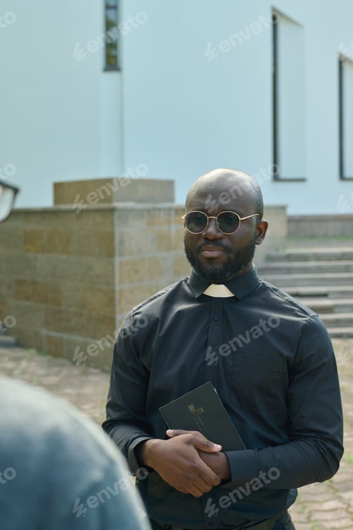 Preview: African American pastor in shirt with clerical collar consulting parishioner