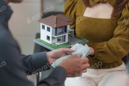 Preview: Real estate agent giving house model to client exchanging money